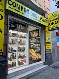 Compro oro en Córdoba, perteneciente a la cadena Oro Atocha. Se muestran carteles amarillos muy llamativos y ofertas para comprar y vender joyas