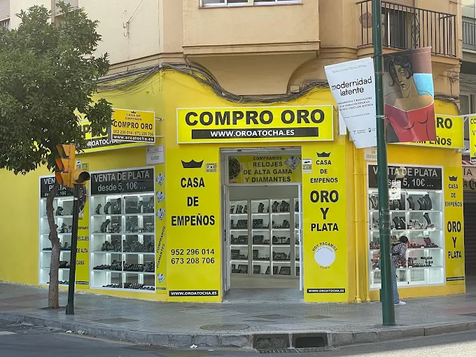 Compro oro en Málaga, perteneciente a la cadena Oro Atocha. Se muestran carteles con sus principales servicios: compra de oro, venta de oro y casa de empeños